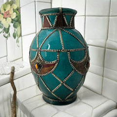 Vintage Moroccan round vase with green glaze, featuring geometric metal decor, four dyed leather inlays with yellow or red bezel-set glass cabochons at their center, and triangle-shaped leather accents around the top, from the 1970s/80s in very good condition.