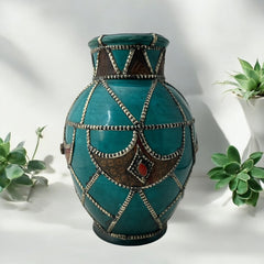 Vintage Moroccan round vase with green glaze, featuring geometric metal decor, four dyed leather inlays with yellow or red bezel-set glass cabochons at their center, and triangle-shaped leather accents around the top, from the 1970s/80s in very good condition.