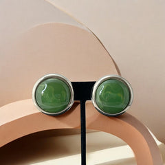 Vintage French button earrings featuring moss green marbled plastic cabochons set in silver tone borders. A classy and elegant 1970s design with retro charm, perfect for sustainable and eco-conscious fashion lovers.