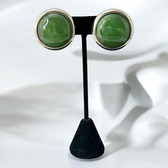 Vintage French button earrings featuring moss green marbled plastic cabochons set in silver tone borders. A classy and elegant 1970s design with retro charm, perfect for sustainable and eco-conscious fashion lovers.