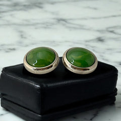 Vintage French button earrings featuring moss green marbled plastic cabochons set in silver tone borders. A classy and elegant 1970s design with retro charm, perfect for sustainable and eco-conscious fashion lovers.