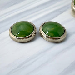 Vintage French button earrings featuring moss green marbled plastic cabochons set in silver tone borders. A classy and elegant 1970s design with retro charm, perfect for sustainable and eco-conscious fashion lovers.
