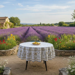 Round coated cotton tablecloth in white with polychrome and blue Provençal motifs, featuring birds, butterflies, and floral designs inspired by traditional Moustiers faience