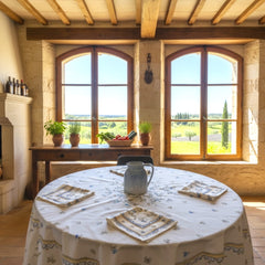 Round coated cotton tablecloth in white with polychrome and blue Provençal motifs, featuring birds, butterflies, and floral designs inspired by traditional Moustiers faience