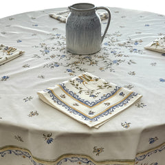 Round coated cotton tablecloth in white with polychrome and blue Provençal motifs, featuring birds, butterflies, and floral designs inspired by traditional Moustiers faience