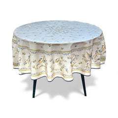 Round coated cotton tablecloth in white with polychrome and blue Provençal motifs, featuring birds, butterflies, and floral designs inspired by traditional Moustiers faience