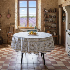 Round coated cotton tablecloth in white with polychrome and blue Provençal motifs, featuring birds, butterflies, and floral designs inspired by traditional Moustiers faience