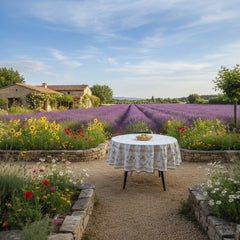 Round coated cotton tablecloth in white with polychrome and blue Provençal motifs, featuring birds, butterflies, and floral designs inspired by traditional Moustiers faience
