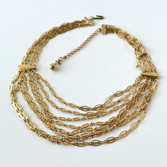 Vintage multi‑strand filigree gold‑tone bib necklace with ornate oval links and adjustable hook clasp.