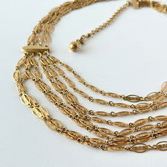 Vintage multi‑strand filigree gold‑tone bib necklace with ornate oval links and adjustable hook clasp.