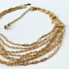 Vintage multi‑strand filigree gold‑tone bib necklace with ornate oval links and adjustable hook clasp.