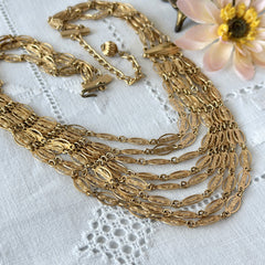 Vintage multi‑strand filigree gold‑tone bib necklace with ornate oval links and adjustable hook clasp.
