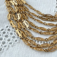 Vintage multi‑strand filigree gold‑tone bib necklace with ornate oval links and adjustable hook clasp.