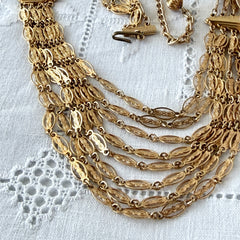 Vintage multi‑strand filigree gold‑tone bib necklace with ornate oval links and adjustable hook clasp.