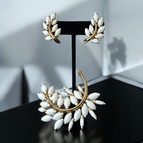 Vintage Napier jewelry set from the Porcelain White Collection (mid-1960s), featuring a gold-plated brass floral brooch with white milk glass stones and matching clip-on earrings. Signed Napier, both pieces are in very good vintage condition.
