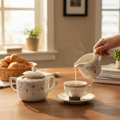 Vintage Nippon porcelain sugar bowl and creamer set with hand-painted gold floral design on white glaze; sugar bowl with dual handles and lid, creamer with spout and single handle; both marked “Hand Painted Nippon” with sun emblem on base.