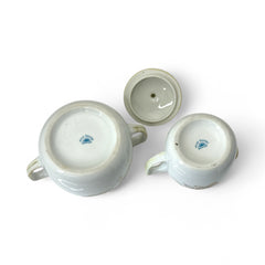 Vintage Nippon porcelain sugar bowl and creamer set with hand-painted gold floral design on white glaze; sugar bowl with dual handles and lid, creamer with spout and single handle; both marked “Hand Painted Nippon” with sun emblem on base.