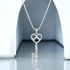 Vintage Nolan Miller silver-tone key pendant necklace with clear rhinestones in heart and infinity design, shown on twisted rope chain.