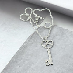 Vintage Nolan Miller silver-tone key pendant necklace with clear rhinestones in heart and infinity design, shown on twisted rope chain.