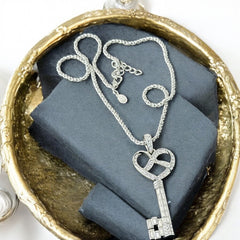 Vintage Nolan Miller silver-tone key pendant necklace with clear rhinestones in heart and infinity design, shown on twisted rope chain.