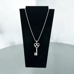 Vintage Nolan Miller silver-tone key pendant necklace with clear rhinestones in heart and infinity design, shown on twisted rope chain.