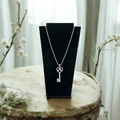 Vintage Nolan Miller silver-tone key pendant necklace with clear rhinestones in heart and infinity design, shown on twisted rope chain.