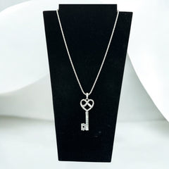 Vintage Nolan Miller silver-tone key pendant necklace with clear rhinestones in heart and infinity design, shown on twisted rope chain.