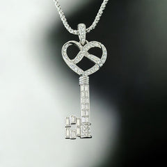 Vintage Nolan Miller silver-tone key pendant necklace with clear rhinestones in heart and infinity design, shown on twisted rope chain.