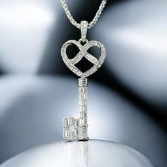 Vintage Nolan Miller silver-tone key pendant necklace with clear rhinestones in heart and infinity design, shown on twisted rope chain.