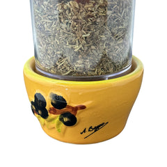 Provence hand-painted ceramic herb grinder with a yellow base featuring black olive and green leaf design, filled with dried Herbes de Provence. 