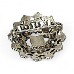 Vintage silver tone brooch with ornate round filigree design, featuring a central opalite heart cabochon and pastel rhinestones in pink, blue, yellow, and lavender—shown front and back to highlight detailing and clasp.