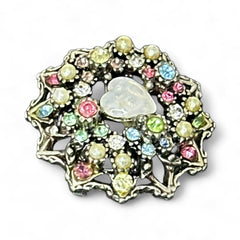 Vintage silver tone brooch with ornate round filigree design, featuring a central opalite heart cabochon and pastel rhinestones in pink, blue, yellow, and lavender—shown front and back to highlight detailing and clasp.