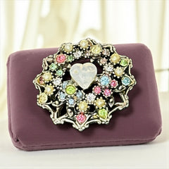 Vintage silver tone brooch with ornate round filigree design, featuring a central opalite heart cabochon and pastel rhinestones in pink, blue, yellow, and lavender—shown front and back to highlight detailing and clasp.