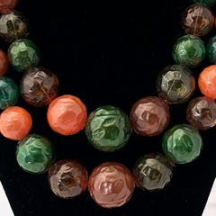Vintage 1950s 2-strand graduated necklace featuring transparent and opaque orange and green plastic beads, finished with gold-tone findings and an adjustable hook clasp, in very good vintage condition.