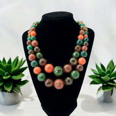 Vintage 1950s 2-strand graduated necklace featuring transparent and opaque orange and green plastic beads, finished with gold-tone findings and an adjustable hook clasp, in very good vintage condition.