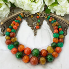 Vintage 1950s 2-strand graduated necklace featuring transparent and opaque orange and green plastic beads, finished with gold-tone findings and an adjustable hook clasp, in very good vintage condition.