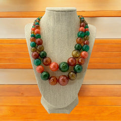 Vintage 1950s 2-strand graduated necklace featuring transparent and opaque orange and green plastic beads, finished with gold-tone findings and an adjustable hook clasp, in very good vintage condition.