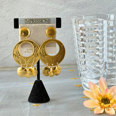 Vintage 1980s gold‑tone circle dangle post earrings with embossed paisley design and dangling discs, displayed on original Impressions card.