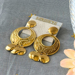Vintage 1980s gold‑tone circle dangle post earrings with embossed paisley design and dangling discs, displayed on original Impressions card.