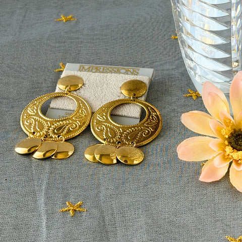 Vintage 1980s gold‑tone circle dangle post earrings with embossed paisley design and dangling discs, displayed on original Impressions card.