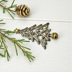 Vintage Paquette Christmas tree brooch in silver and gold-tone metal, featuring a modernist design with circular cutouts and a gold star at the top; signed on the back, circa 1990s, in very good condition.