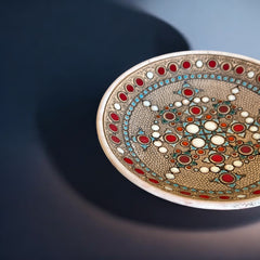 Vintage French studio pottery bowl by Paul Dordet, hand-formed in textured buff clay with red, white, and blue glazed circular motifs; signed on the underside and shown with hanging wire for optional wall display.