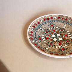 Vintage French studio pottery bowl by Paul Dordet, hand-formed in textured buff clay with red, white, and blue glazed circular motifs; signed on the underside and shown with hanging wire for optional wall display.