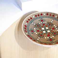 Vintage French studio pottery bowl by Paul Dordet, hand-formed in textured buff clay with red, white, and blue glazed circular motifs; signed on the underside and shown with hanging wire for optional wall display.