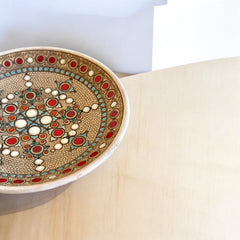 Vintage French studio pottery bowl by Paul Dordet, hand-formed in textured buff clay with red, white, and blue glazed circular motifs; signed on the underside and shown with hanging wire for optional wall display.