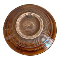 Vintage French studio pottery bowl by Paul Dordet, hand-formed in textured buff clay with red, white, and blue glazed circular motifs; signed on the underside and shown with hanging wire for optional wall display.