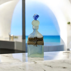 Vintage Romanian art glass perfume bottle from the 1990s, featuring frosted blue and green glass with a sculptural swirled stopper and bronze wire bow detail around the neck. Square base with a tapered neck; dauber slightly shortened due to breakage.