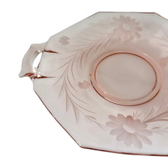 Vintage pink Depression glass serving dish with etched floral design and dual handles, styled on marble with soft lighting to highlight its shape, color, and collectible charm.