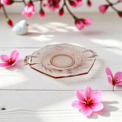 Vintage pink Depression glass serving dish with etched floral design and dual handles, styled on marble with soft lighting to highlight its shape, color, and collectible charm.
