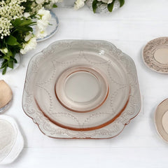 Vintage pink depression glass set featuring 2 delicate cups from the American Sweetheart collection and 2 square saucers from the Madrid collection, both adorned with intricate floral and geometric etched patterns. A timeless and sustainable addition to any table or décor.